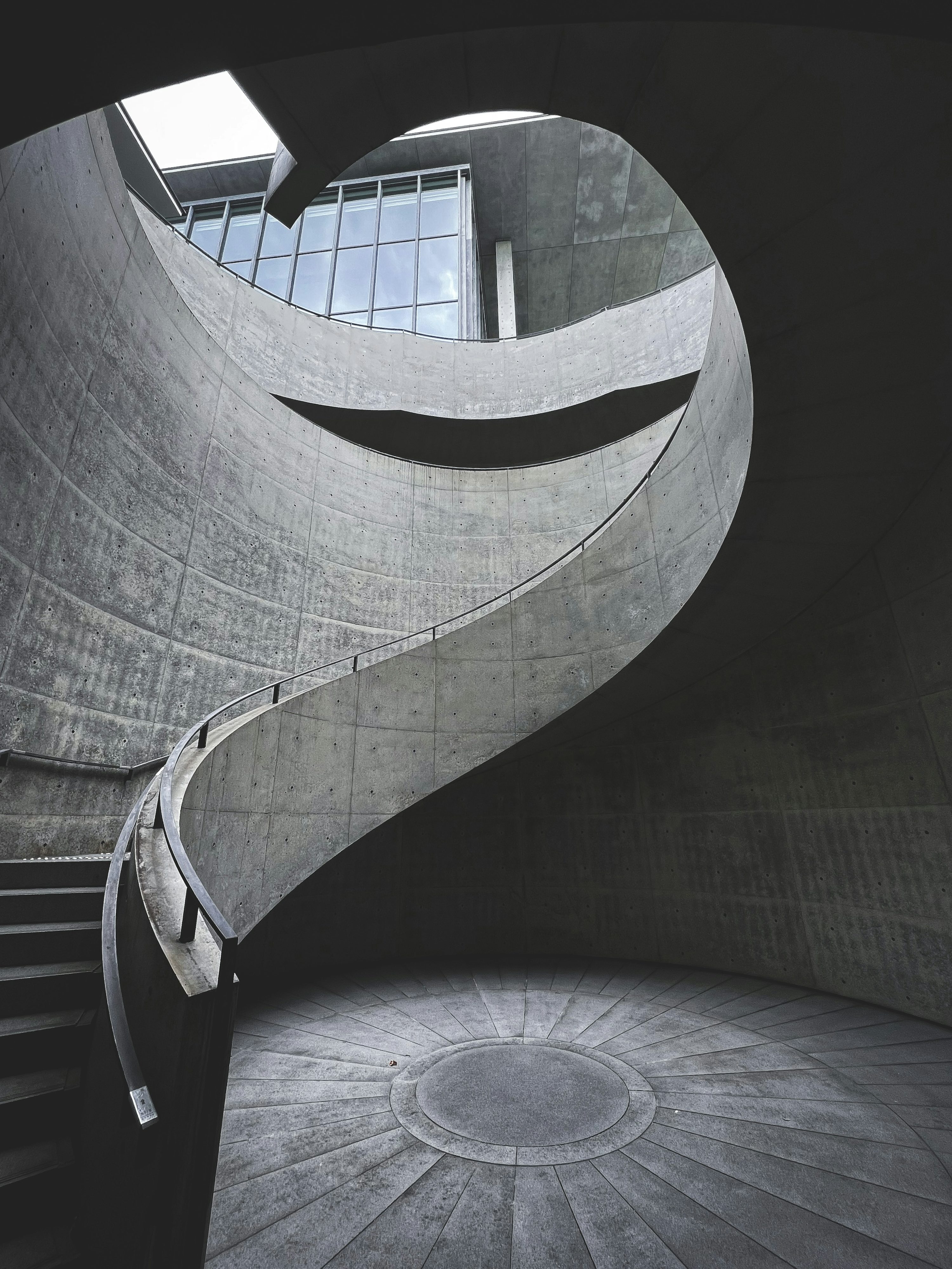 A sculptural staircase rising towards an open circular window